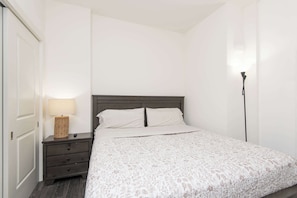 A bedroom with a bed, a nightstand, a lamp, and a wardrobe. - Hollywood 2BR apt w Rooftop deck & Stunning Views (Los Angeles)