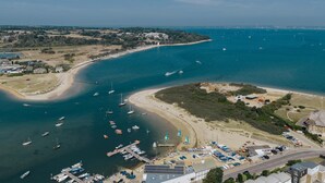 Luchtbeeld van een kustgebied met een jachthaven, strand en gebouwen.