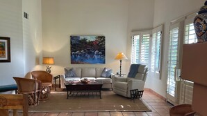 Ein Wohnzimmer mit einer Couch, Sesseln, einem Couchtisch und einem Bild an der Wand.
