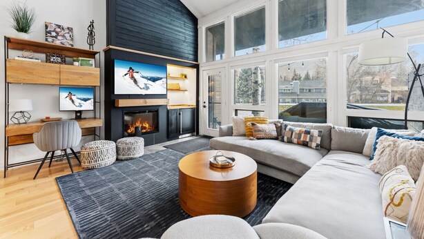 Una sala de estar moderna con chimenea, ventanas amplias y un rincón de descanso acogedor.