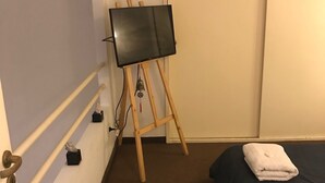 Ett hotellrum med en säng, en tv på ett stativ och en dörr som leder till ett annat rum.