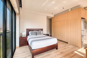 Une chambre moderne avec un grand lit, un plancher en bois, une table de chevet et une armoire.