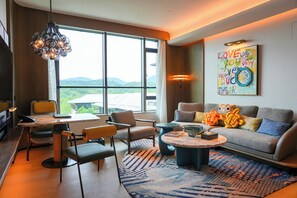 Ein modernes Wohnzimmer mit großem Fenster, einer Couch, einem Couchtisch und einem Essbereich.