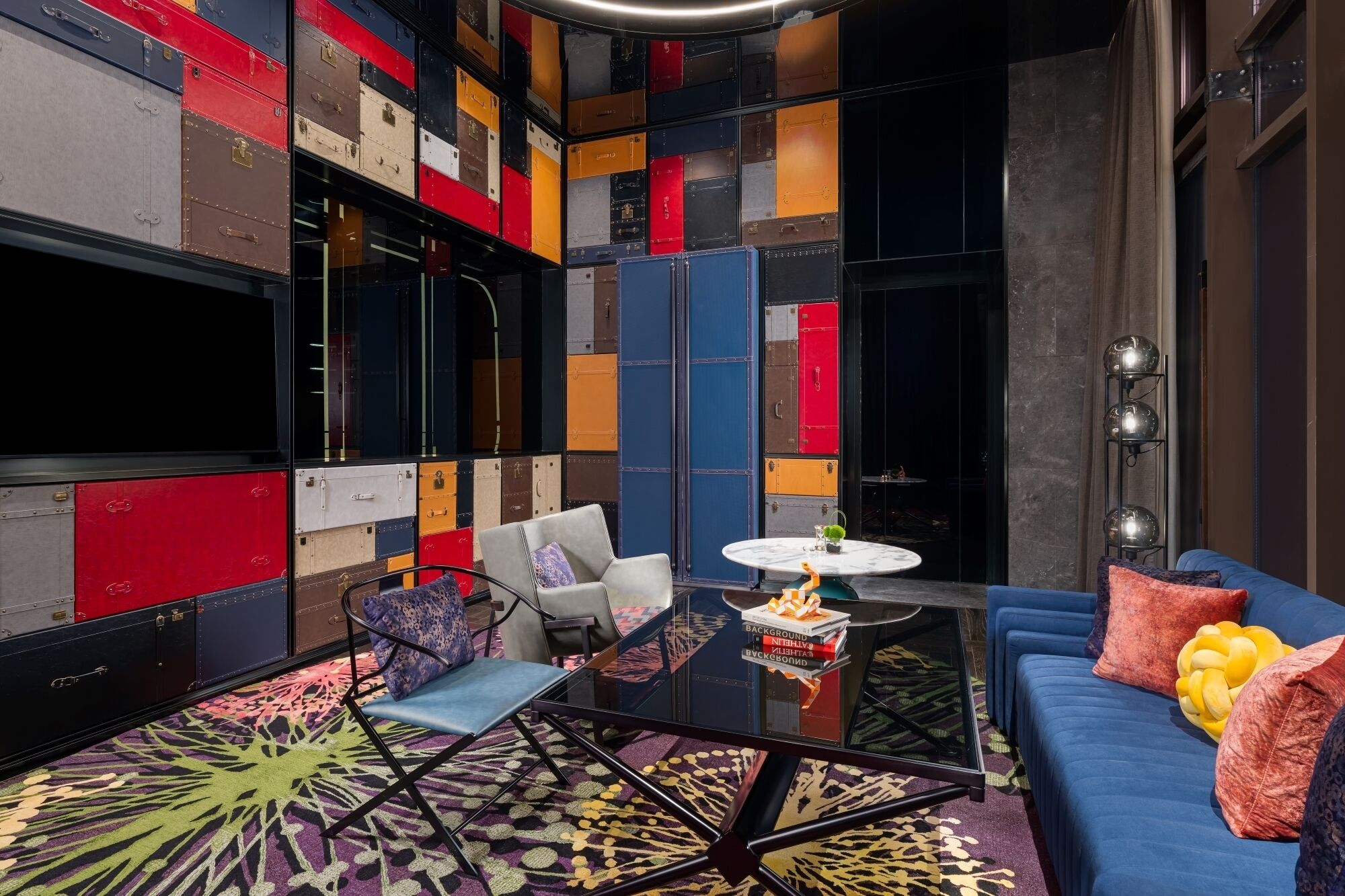 A modern room with a blue sofa, a round table, and colorful storage units.
