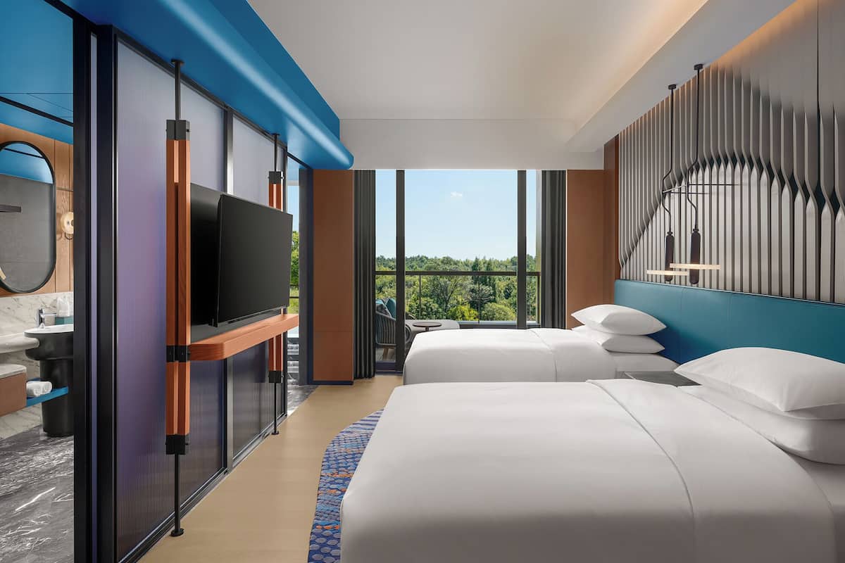Habitació d'hotel moderna amb una finestra gran, televisió de pantalla plana, un llit i zona de seients.