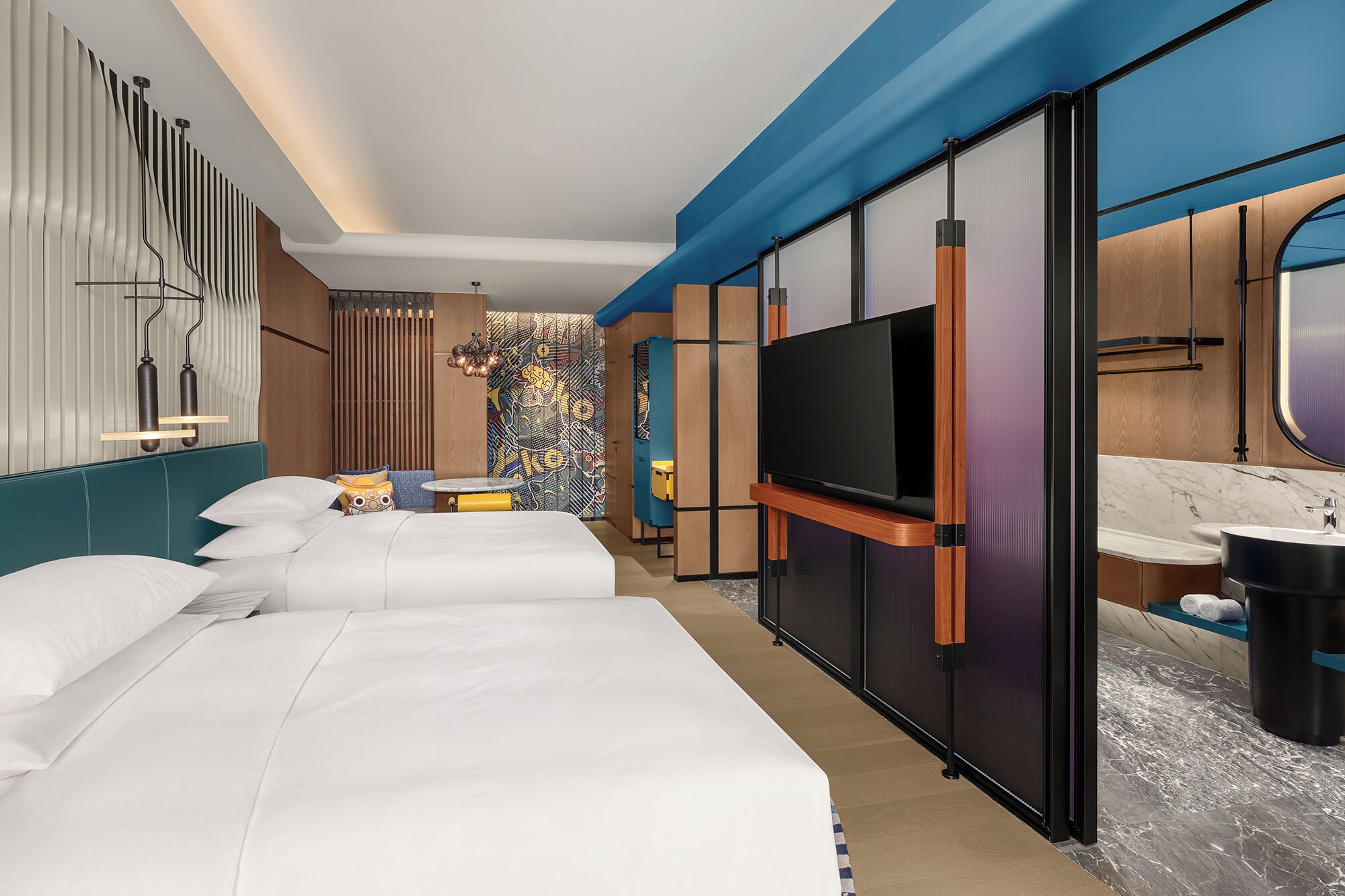 A modern hotel room with two beds, a TV, a bathroom with a marble countertop, and a unique patterned wall.