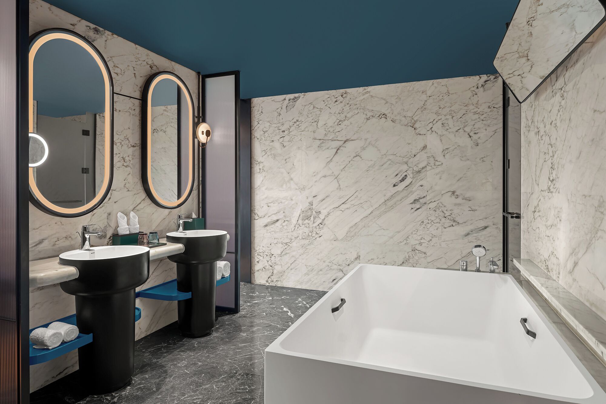 A modern bathroom with two sinks, a large bathtub, and three mirrors.