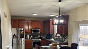 Une cuisine moderne avec des meubles en bois, des appareils en acier inoxydable et un coin repas comprenant une table et des chaises.