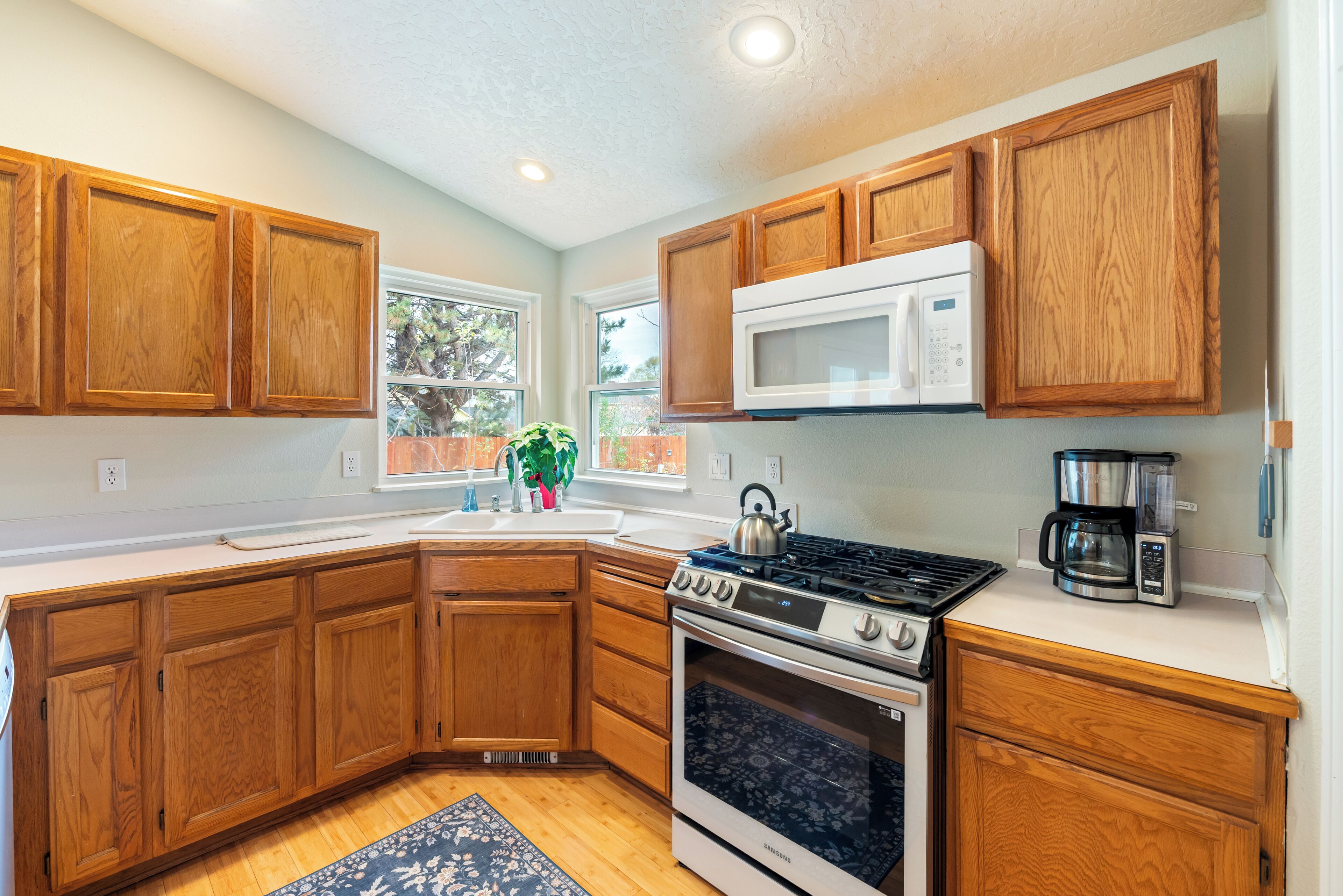 A kitchen with wooden cabinets, a microwave, a stove, and a coffee maker.
