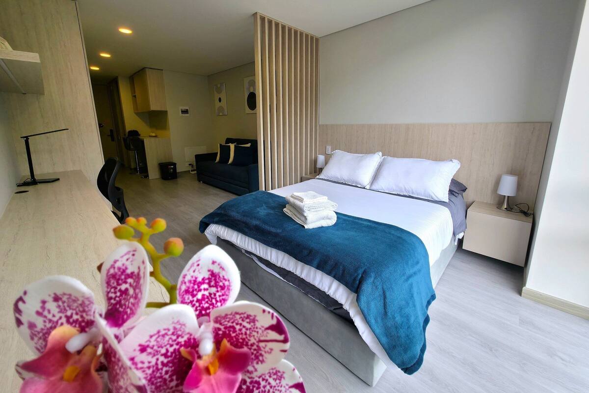 Ein Hotelzimmer mit Bett, Nachttisch und Schreibtisch mit Stuhl.
