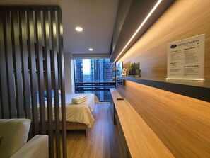 A modern hotel room with a bed, a desk, a potted plant, and a welcome sign. - North Point Hills 2 (Bogotá)