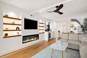 A modern living room with a fireplace, television, and built-in shelves.