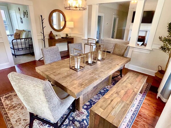 A dining area with a wooden table, cushioned chairs, and a chandelier.