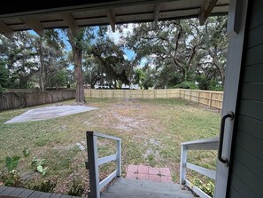A backyard with a wooden deck, a grassy lawn, and a wooden fence.