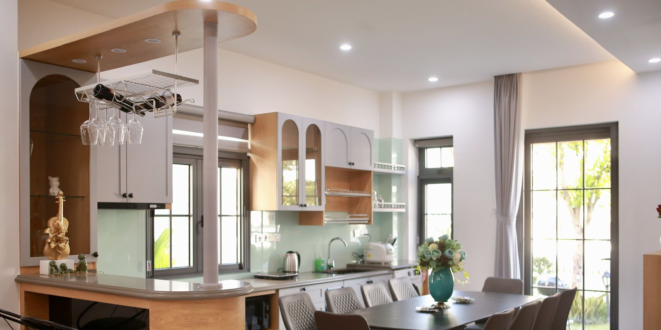 A modern kitchen with a central island, built-in cabinets, and a dining area with chairs.