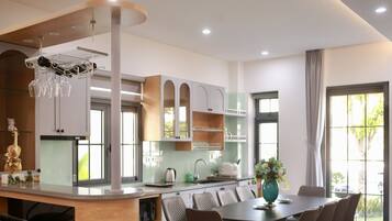 A modern kitchen with a central island, built-in cabinets, and a dining area with chairs.