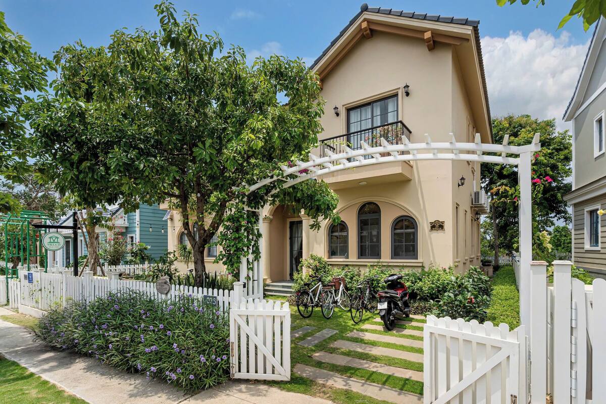 A house with a white picket fence, a covered porch, and a bicycle parked in front.