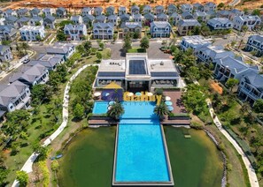 An aerial view of a residential area with modern houses, a central swimming pool, and a building with a sign that reads "Gatuy". - Le Gia Villa Nova World Phan Thiet (Tien Thanh)