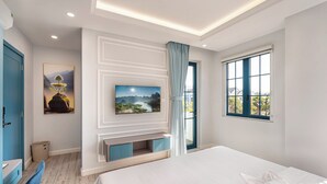 Ein modernes Hotelzimmer mit einem großen Bett, einem flachbildfernseher an der Wand, einer kleinen Sitzecke und einem Fenster mit Außenblick.