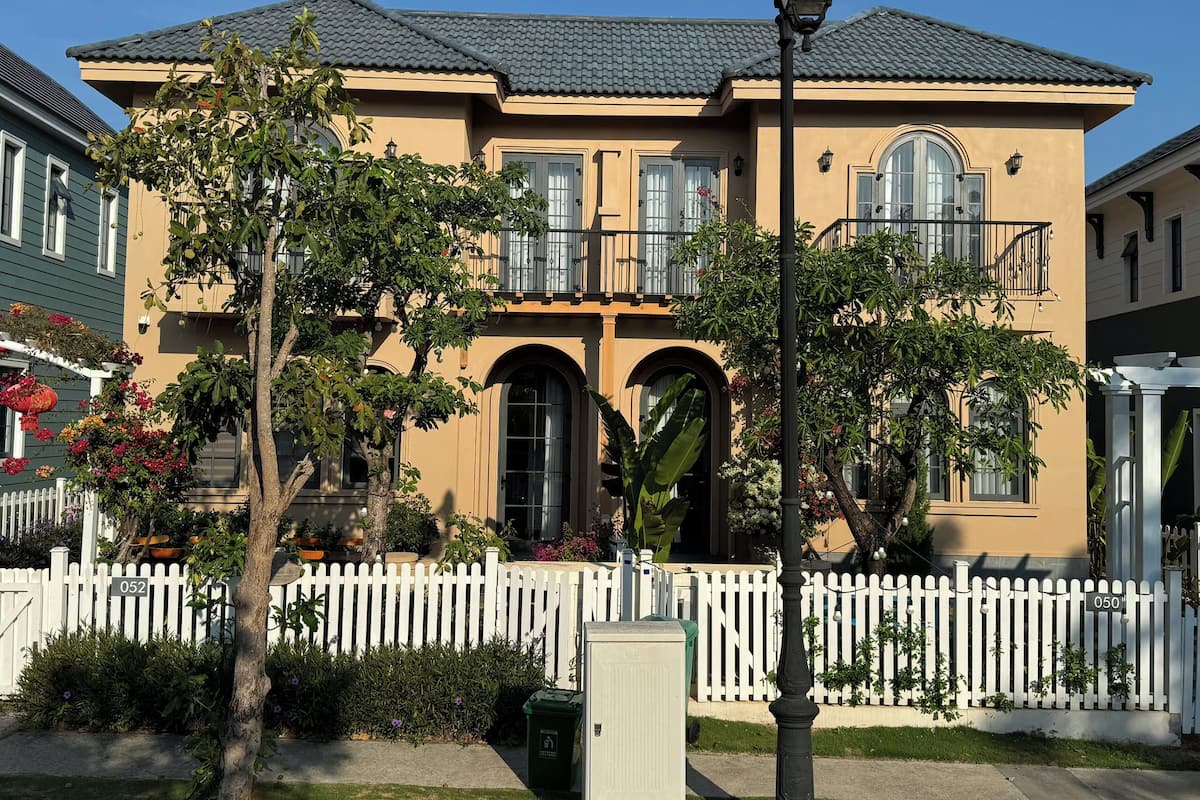 A two-story house with a white picket fence, a balcony, and a street lamp.