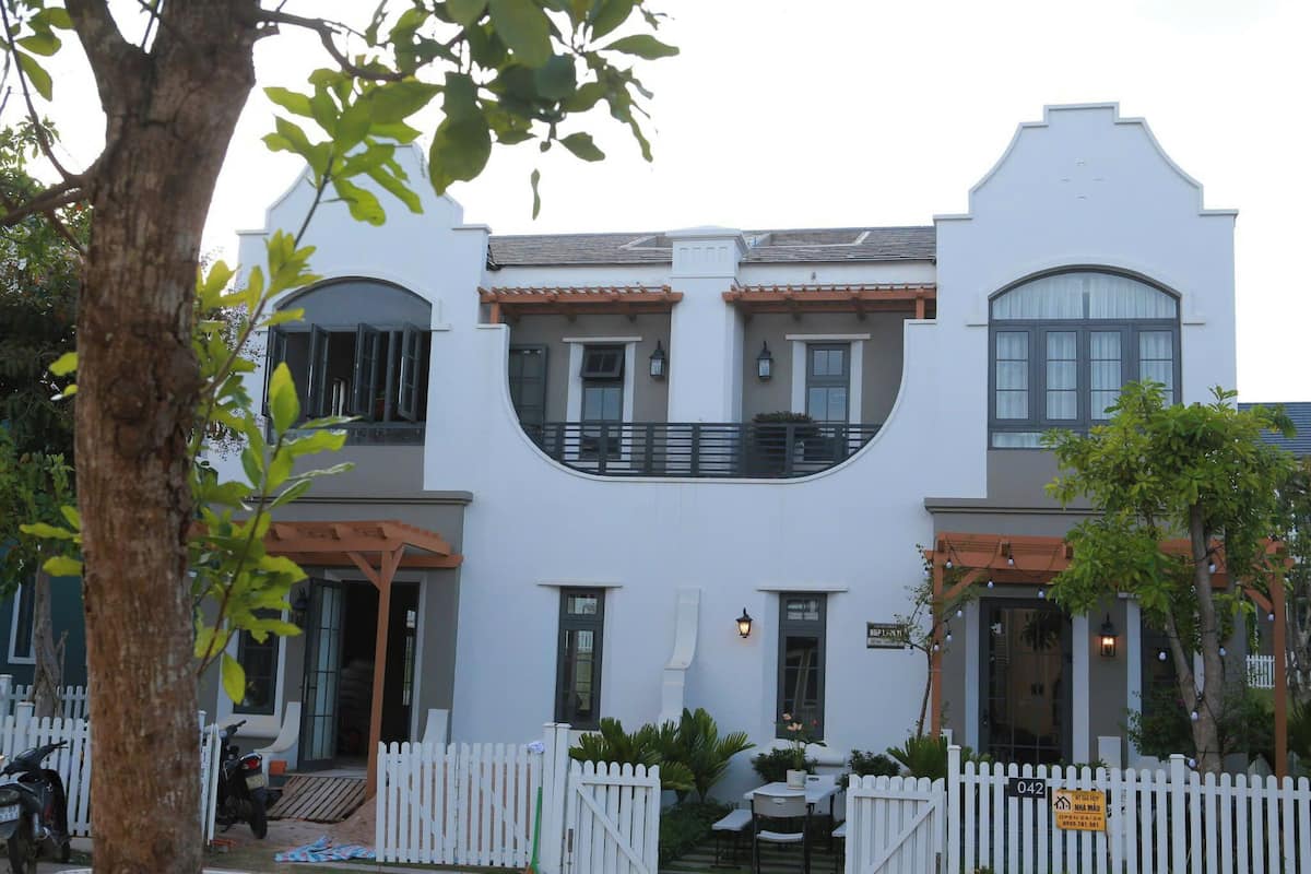 A two-story building with a white facade, a balcony, and a white picket fence.
