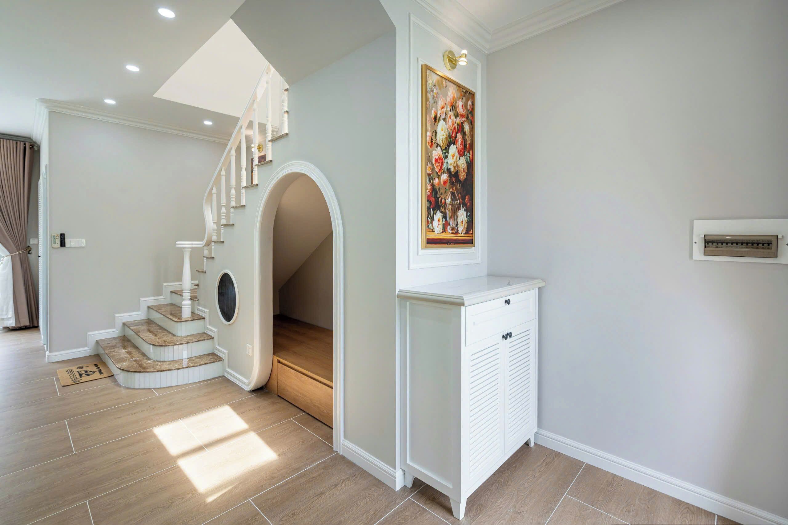 A modern interior with a staircase, a decorative painting, and a white cabinet.