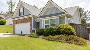 A residential house with a garage, a brick section, and a well-maintained lawn.