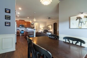 A modern kitchen with stainless steel appliances, wooden cabinets, and pendant lighting.