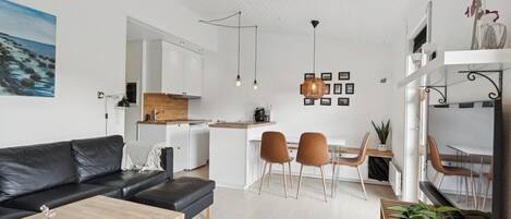 A modern living space with a sofa, dining area, kitchen, and a TV.