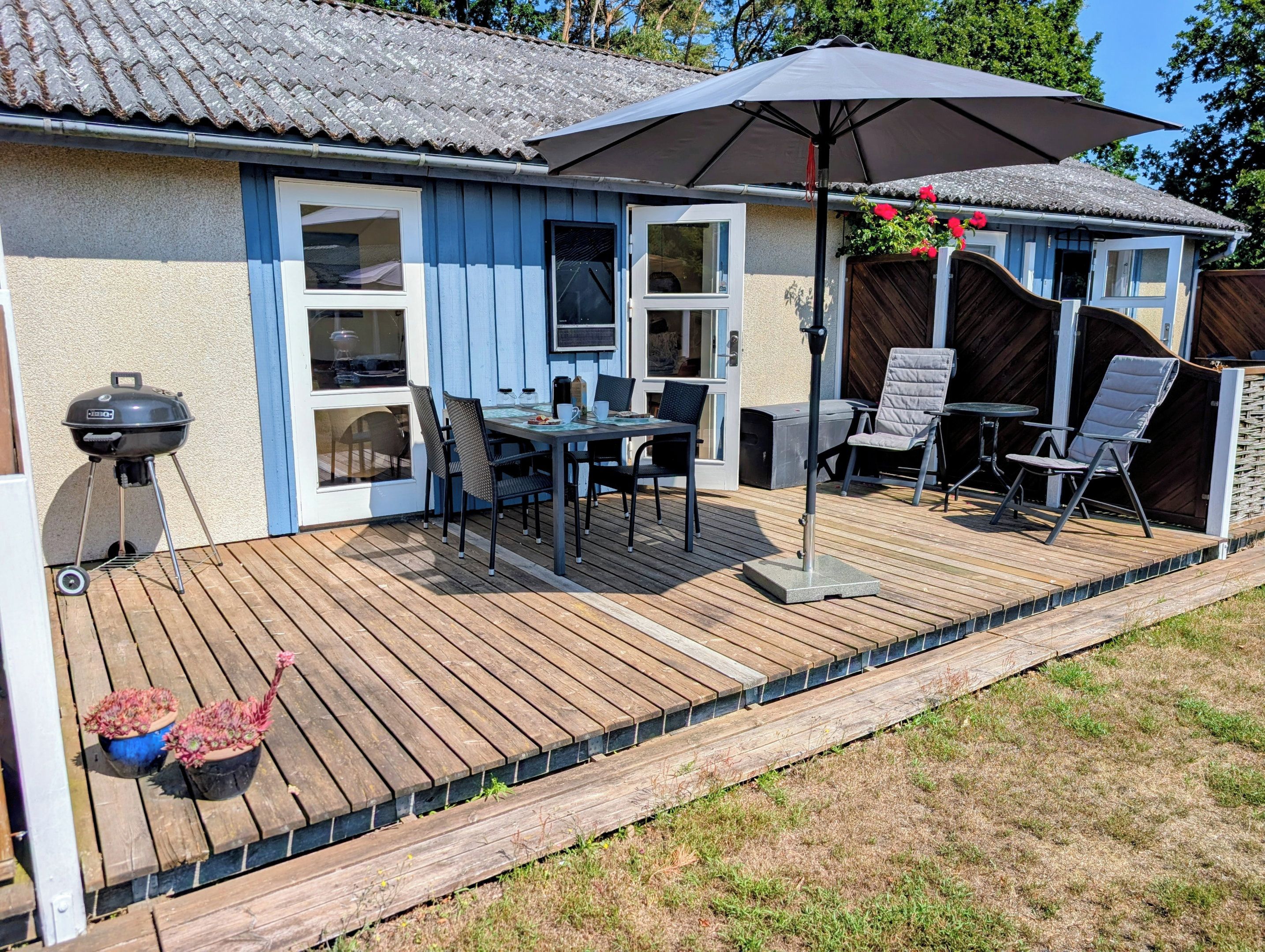 A patio with a table and chairs, a grill, and a covered area with an umbrella.