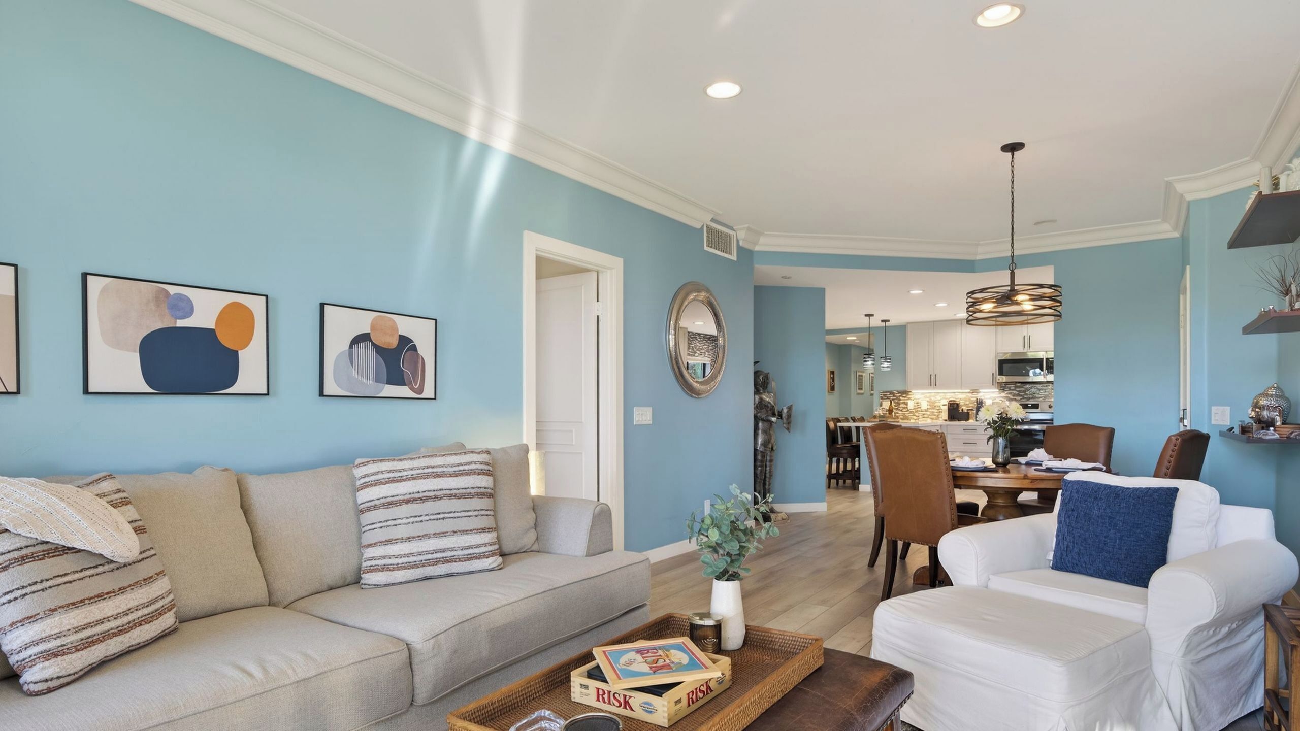 A living room with a sofa, a coffee table with a tray, and a dining area with chairs and a table.