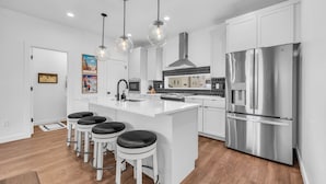 A modern kitchen with white cabinetry, stainless steel appliances, and a central island with bar stools. - Wasatch Mountain Retreat. Your Ultimate Mountain Gateway in Mountain Green, Utah (Mountain Green)