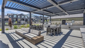 An outdoor patio area with seating, a grill, and a view of residential buildings. - Wasatch Mountain Retreat. Your Ultimate Mountain Gateway in Mountain Green, Utah (Mountain Green)
