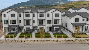 A row of modern, multi-story residential buildings with a uniform architectural style, featuring balconies and a well-maintained front yard with a wooden fence. - Wasatch Mountain Retreat. Your Ultimate Mountain Gateway in Mountain Green, Utah (Mountain Green)