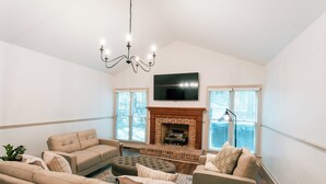A living room with a fireplace, sofas, and a TV. - Raleigh Risque’ Room - Couples’ Retreat & Playroom (Raleigh)