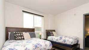 Ein Schlafzimmer mit zwei Betten, einem Fenster und einer Tür.