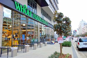 A Whole Foods Market with a glass storefront, outdoor seating, and a tow-away sign. - Rooftop Pool Views · Modern 2BR City Retreat (Los Angeles)