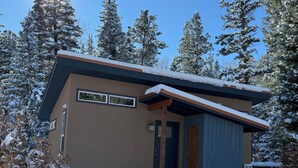 Eine moderne Hütte mit brauner Fassade, einer Holztür und einer kleinen Veranda.