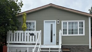 A single-story building with a front door, a small porch, and a gravel driveway.