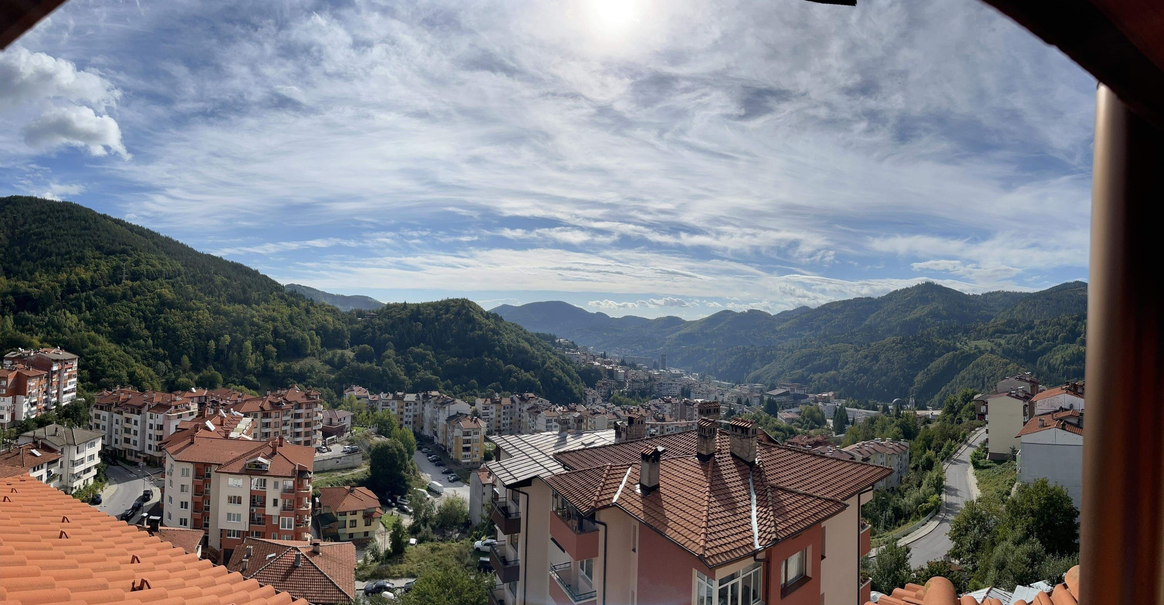 A residential area with buildings, roads, and mountains in the background.