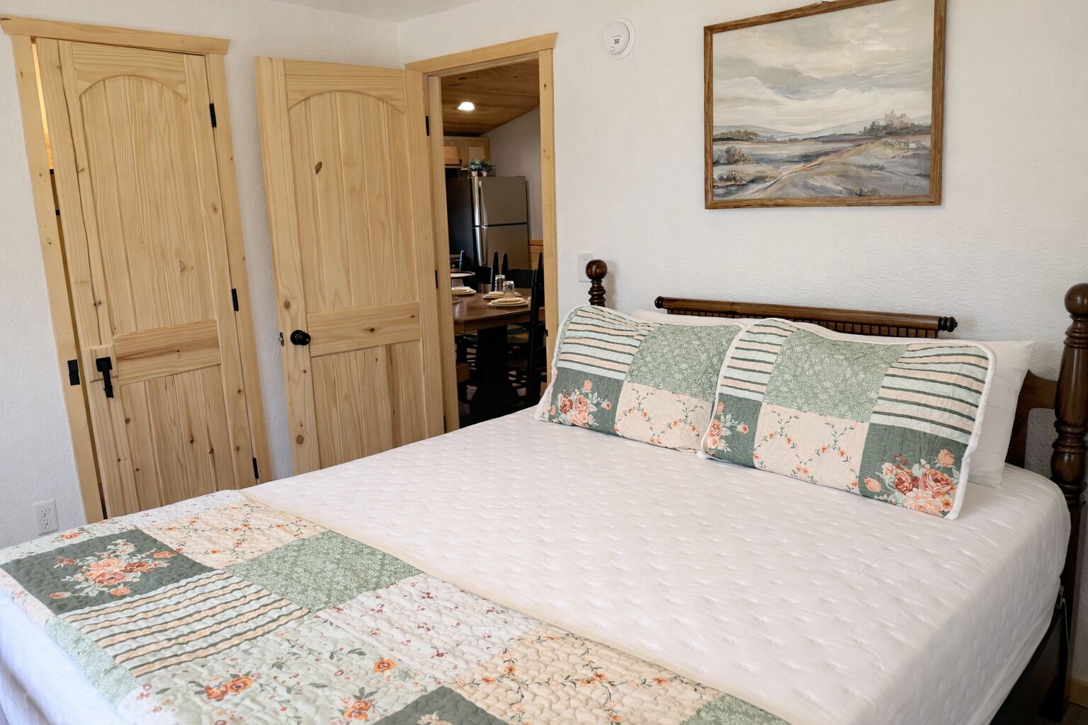 Une chambre à coucher avec un lit, une armoire en bois et un tableau accroché au mur.