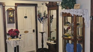 Ein Zimmer mit Holzboden, einem Esstisch mit Stühlen, einer Uhr, einem Spiegel und einer Vitrine mit Glastüren.