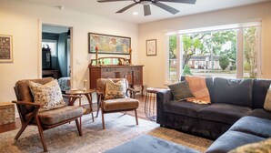 A living room with a ceiling fan, a dark-colored sofa, two armchairs, a small table, and a cabinet.