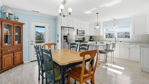 Une cuisine moderne avec des meubles blancs, un îlot central et une table à manger avec des chaises.