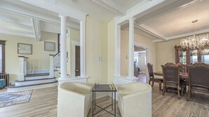 Un salón espacioso con chimenea, un comedor con candelabro y una escalera que sube a otro nivel.