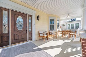 A covered porch with wooden furniture and a white ceiling. - Grand Richmond Beach Retreat (Atlantic City)