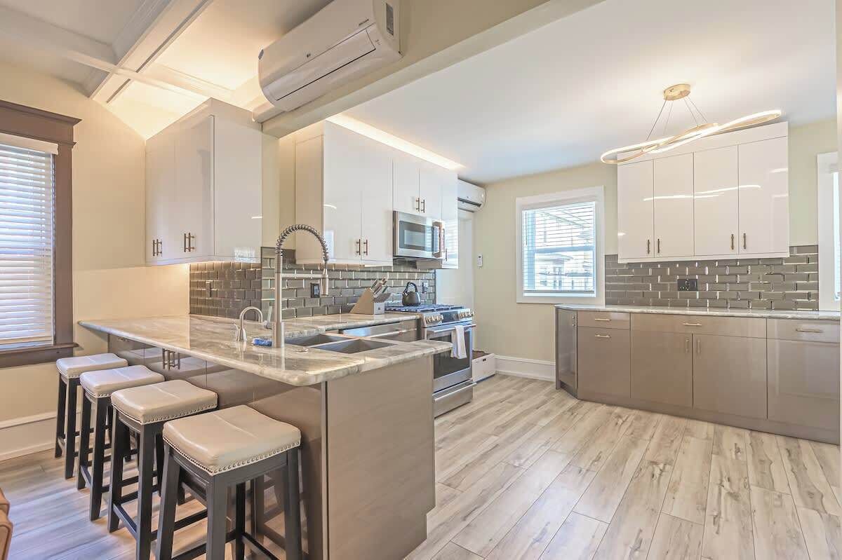 A modern kitchen with a central island, bar stools, and a large window.