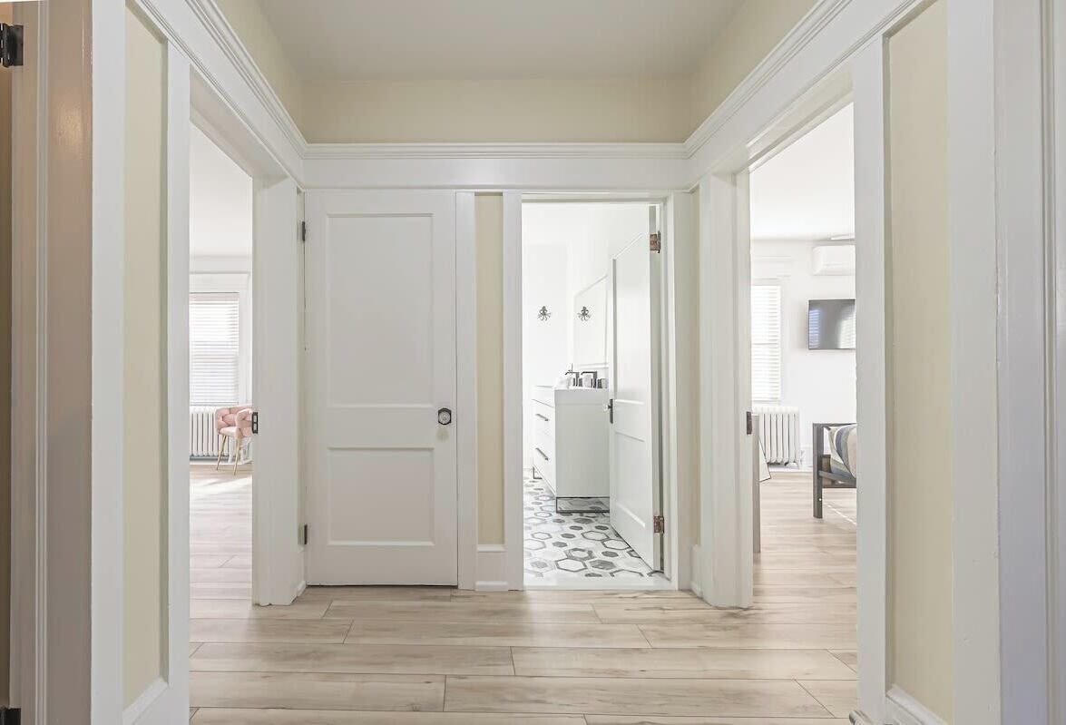 Un pasillo con una puerta blanca, piso estampado y vista a un área de cocina.