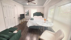 A bedroom with a bed, a TV, a ceiling fan, a window with blinds, a green sofa, and a chair. - Serene 4-bedroom house perfect for relaxing stays in Decatur near Atl downtown (Decatur)