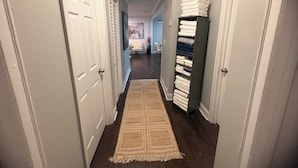 A hallway with a patterned rug, a stack of folded towels, and a door on the left. - Serene 4-bedroom house perfect for relaxing stays in Decatur near Atl downtown (Decatur)